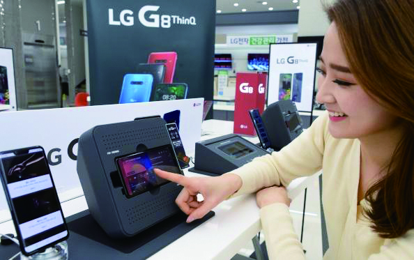 LG 베스트샵 붐박스부스터에 거치된 스마트폰 G8의 스테레오 사운드를 체험해보고 있다. 자료: LG전자