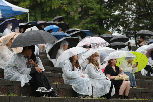 학생들이 우산을 쓰고 주간 부스를 둘러 보고 있다.